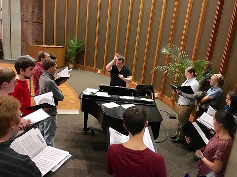 photo of Chris Petit at the piano directing students during practice